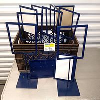 Blue metal stand sign holders in two sizes arranged inside a crate to show the group of eleven units.