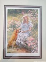 Full view of the framed art print depicting a young woman in a white dress and hat seated among flowers with a golden retriever.