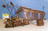 Side angle showing the entire copper covered bridge sculpture, mounted with metal flowers and treelike branches.