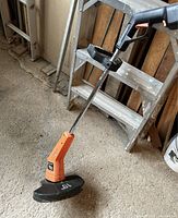 Whole unit of the Black and Decker Whipper Snipper showing orange body and black cutting guard with '10"' marking.