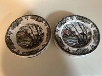 Stack of 4 Friendly Village soup bowls and stack of 5 Friendly Village dessert plates, showing black and white rural scene with scalloped leaf border.