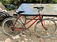 Side profile of red vintage Road King bicycle showing steel frame, tires, fenders, rear rack, and drivetrain.