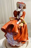 Front view of Royal Doulton Pretty Ladies figurine showing lady in orange dress and hat