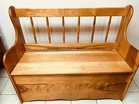 Front view of solid wood storage bench showing seat and spindle backrest