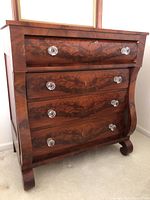 Full front-angle view showing bombe-curved sides, four drawers, crystal knobs and bracket feet