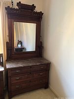 Front view of dresser and mirror showing marble top, three drawers, carved wood details and hardware