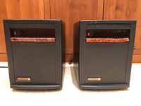 Front view of two identical EdenPure quartz infrared portable heaters side by side on a carpeted floor in front of wooden paneling.