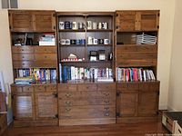 Full view of three matching Ethan Allen wooden bookshelves filled with books, mugs, and various items to illustrate size and configuration.