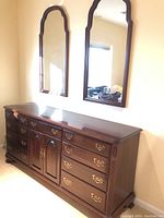 Front view of dresser with two matching mirrors hung above.