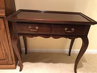 Front view of the wooden foyer table showing two drawers with brass handles and curved legs.