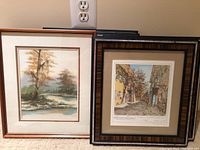 Two framed art pieces visible; one nature landscape, one detailed street scene with autumn foliage.