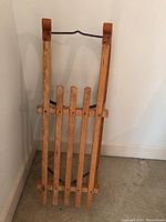 Front angled view showing the vertical wood slats seat and padded leather caps on runners.