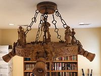Side angle of the hand carved wooden chandelier showing figurines and floral carving details.