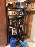 Full view of metal shelving holding various tools and boxes including Black & Decker jig saw box, latched toolbox, power cords, and containers.