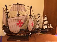 Photo showing both model ships including the Carabela Espanola in the foreground with distinctive red crosses on sails and the Velero Espanol in the background with white sails.