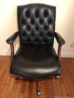 Front view of black leather chair showing tufted back and seat