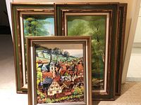 Five framed oil paintings stacked together showing frames and partial artwork.