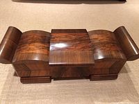 Front view showing the closed curved lid of the wooden sewing box with rich wood grain and glossy finish