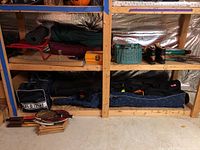 Wide view of shelving with fishing gear, racquets, boots, seat, and ski equipment