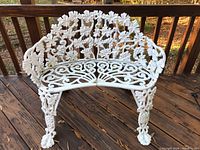 Front and top view of the white painted wrought iron bench showing grapevine design and curved seat with split sections.