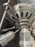 Close-up photo of one ceiling fan showing metal housing, vented design, and three light fixtures