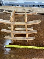 Top view photo showing the wooden wine rack placed on a wooden surface, with a measuring tape indicating the width around 12 inches.