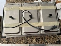 Top view of chafing dish showing three lids taped down and power cord resting on top.