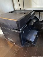 Black HP laser printer with wireless capabilities, showing the left-front side, top document feeder, and output tray.