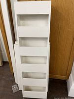 White baltic birch wood magazine rack standing upright, showing front view with horizontal slats forming compartments.