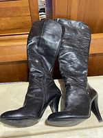 Black Nine West knee-high leather boots displayed standing side by side showing exterior design and height.