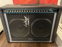 Front view of black Peavey Stereo Chorus 212 amplifier showing two 12-inch speakers behind a mesh grille and the full control panel with knobs across the top.