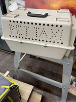 Side view of beige plastic pet carrier showing 'PET TAXI' ventilation holes.