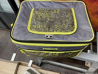 Top and front side view of portable cooler bag showing zippered closure and patterned flap pocket with Outbound brand logo.