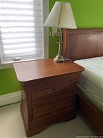 Cherry wood nightstand with brass table lamp, showing finish, drawers, and hidden drawer feature