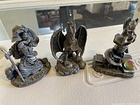 Photo of three fantasy figurines: wizard, dragon, and rabbit wizard figurine with a crystal ball.