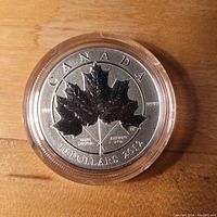Front side of silver coin showing large maple leaf and inscriptions including "CANADA 10 DOLLARS 2012" and purity "9999" marks.
