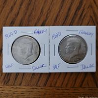 Obverse sides of two 1969 D Kennedy Half Dollar coins in white cardboard holders marked with date and type.