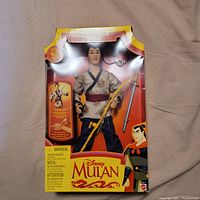Front view of the Disney Mulan Captain Li Shang doll in original packaging, displaying the doll and its accessories clearly through the windowed box.