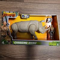 Front view of Jumanji Charging Rhino and male figure in original box showing branding and packaging details.