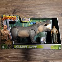 Front view of boxed Jumanji Massive Hippo figure and Rock action figure with packaging showing Jumanji branding and jungle background