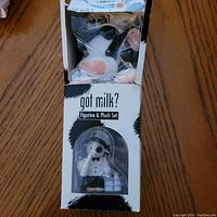 Photo showing the Mary Moo Moos figurine in clear plastic window with box that has noticeable damage.