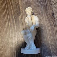 Front view of white sculpture "The Thinker" showing seated male figure resting chin on fist