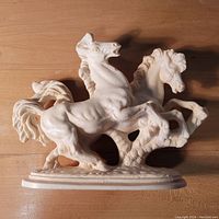 Front angle of white ceramic sculpture showing two horses highly detailed on an oval base