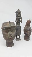 Three bronze statues labeled Benin Nigeria: two heads and one figurative statue.