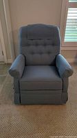Front view of blue Lazy Boy rocker recliner chair showing the tufted backrest with headrest cover and padded armrests.