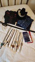 Full overview of men's western clothing set including shirts, jeans, hat, leather belt, bolo ties, and kerchiefs laid out on bed.