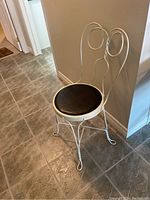 Full side-angle view of the vintage metal wire cafe chair with black leather seat.