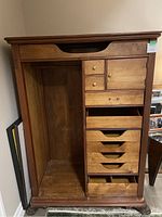Photo of the front of the antique wooden armoire showing open compartments and drawers with wooden knobs, missing outer doors