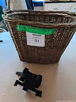 Front and side views of wicker bike basket with metal hooks and mounting bracket below it.