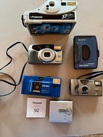 Overview of entire lot with all cameras and music players arranged on table